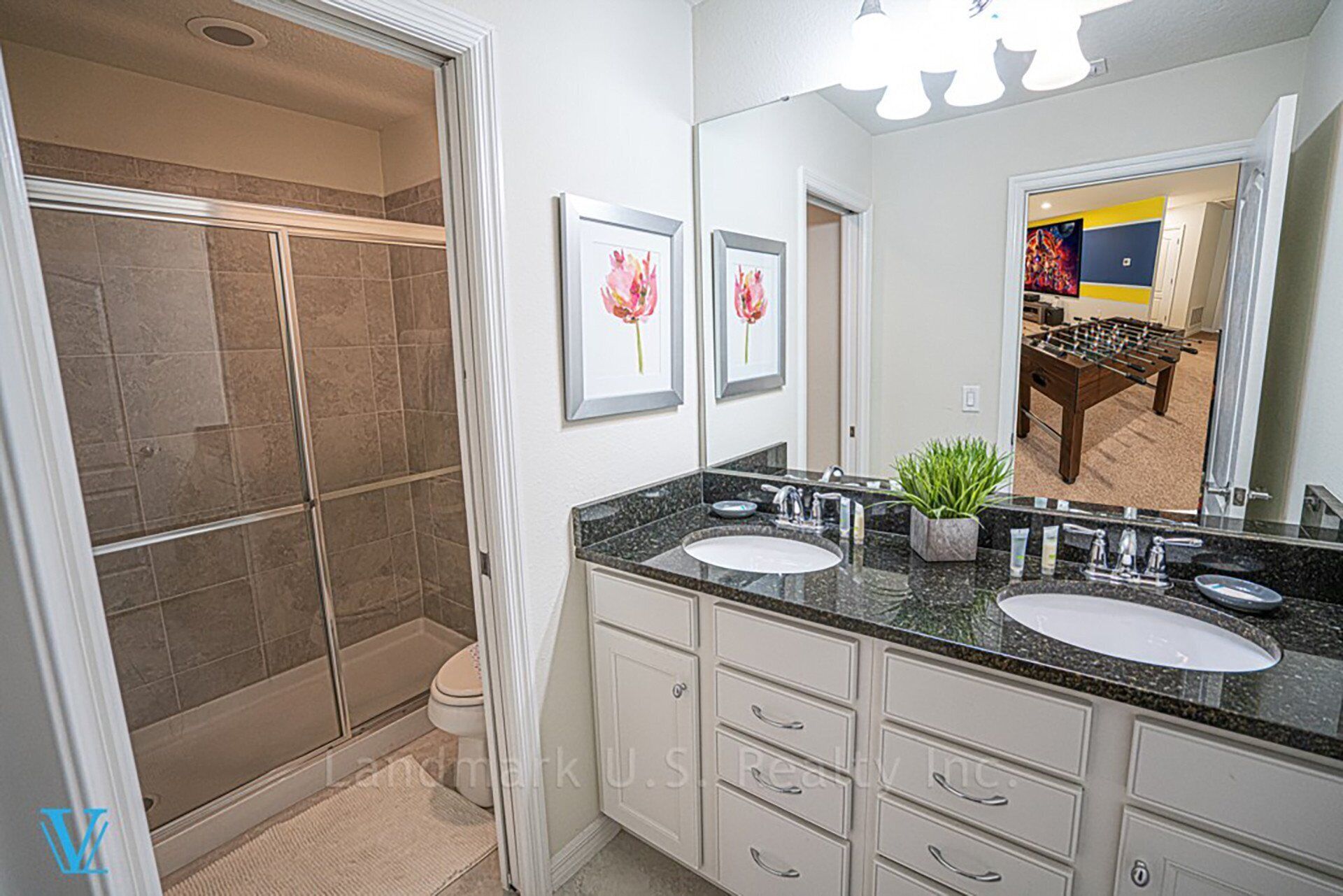 A bathroom with two sinks, a shower, and a large mirror.