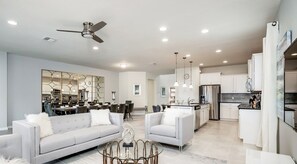 A spacious living area with a modern kitchen, a dining area, and a ceiling fan.