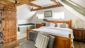A bedroom with a wooden bed, a gray sofa, and a wooden wardrobe.