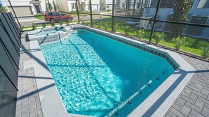 Una piscina rectangular con agua cristalina y azul, rodeada por un bordeado de baldosas y una barrera de vidrio.