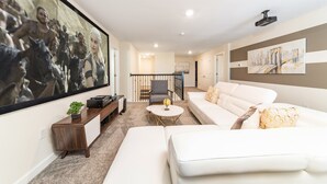 A modern living room with a white sofa, a coffee table, and a TV mounted on the wall. - Last Minute Disney! Private Pool, Hot Tub, Game Room & Themed Bedrooms. Book Now! #38310 (Orlando)