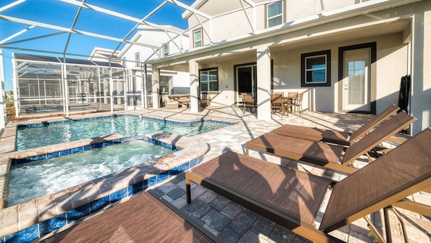 A pool area with lounge chairs and a glass-enclosed structure. - Last Minute Disney! Private Pool, Hot Tub, Game Room & Themed Bedrooms. Book Now! #38310 (Orlando)