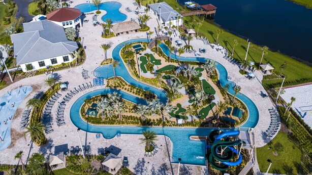 Vue aérienne d’un complexe hôtelier doté de plusieurs piscines, d’un toboggan aquatique et d’un parcours de golf.