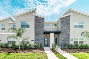 Stucco and stone accents adorn this two-story building, set amidst a beautifully landscaped lawn and lush greenery.