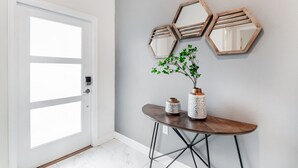 A hallway with a white door, a round wooden table with two vases, and three hexagonal mirrors on the wall. - Last Minute Disney Getaway! Townhouse with Private Pool. Book Now! #49423 (Orlando)