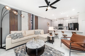 A modern living room with a sectional sofa, a coffee table, and a dining area with chairs. - Last Minute Disney Getaway! Townhouse with Private Pool. Book Now! #49423 (Orlando)