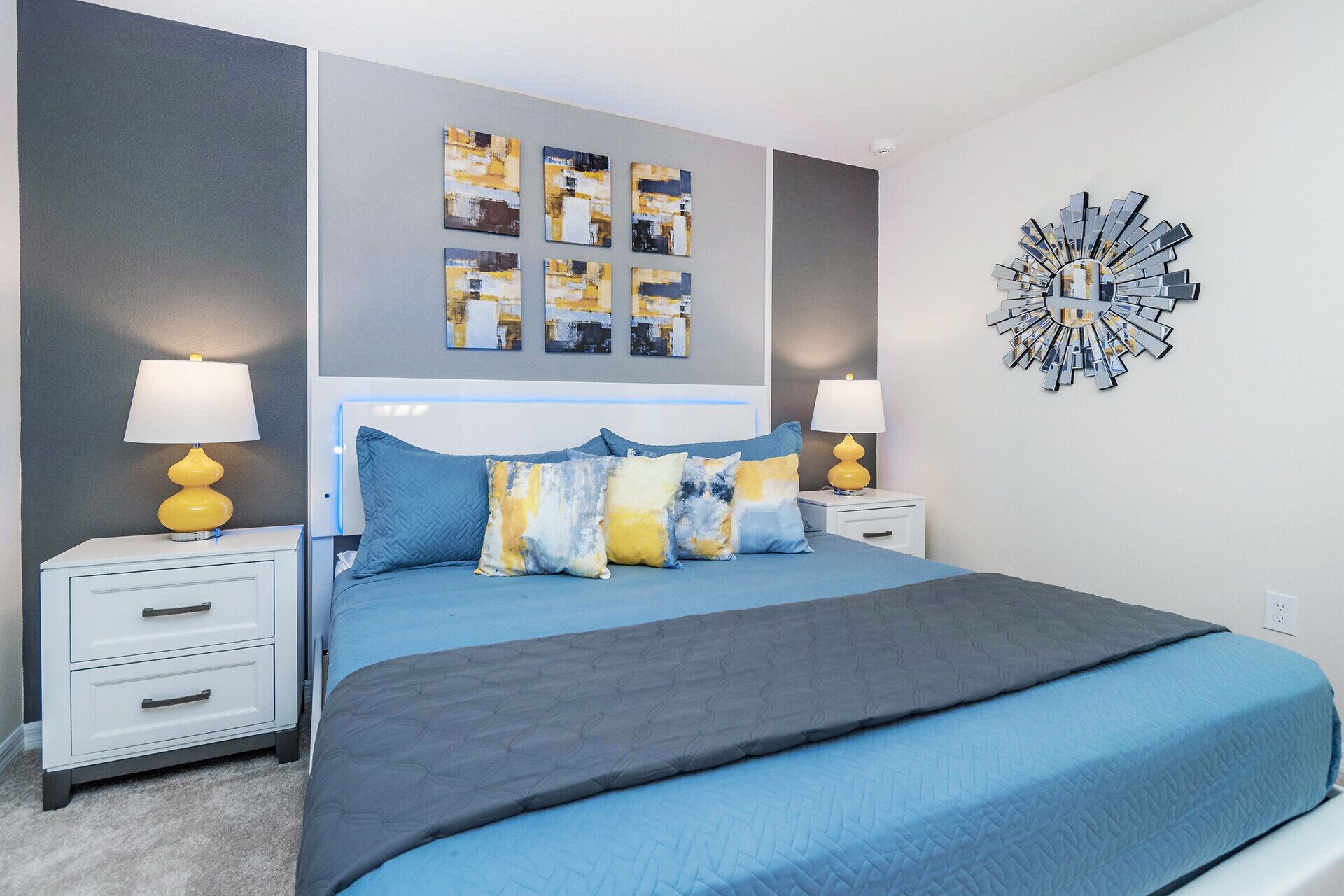 A bedroom with a bed, two bedside tables, a wall clock, and abstract art on the wall.