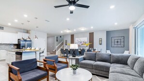 A modern living room with a grey sofa, blue armchairs, and a round coffee table. - Last Minute Disney! Private Pool, Hot Tub & Themed Bedrooms. Book Now! #49467 (Orlando)