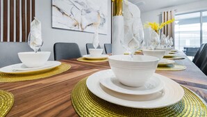 A dining table set with white plates, bowls, and gold placemats, with a vase of yellow flowers in the center. - Last Minute Disney! Private Pool, Hot Tub & Themed Bedrooms. Book Now! #49467 (Orlando)