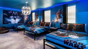 Ett sovrum med Star Wars-tema, med flera sängar, Star Wars-affischer och blått LED-ljus.