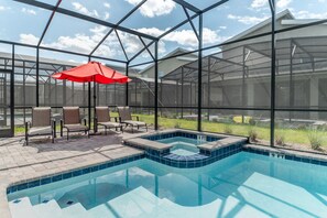 A swimming pool with a hot tub, surrounded by chairs and an umbrella, within a covered area with large windows. - Last Minute Disney! Private Pool, Hot Tub, Game Room & Themed Bedrooms. Book Now! #52927 (Orlando)