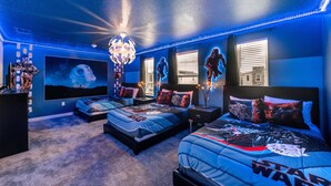Ein Schlafzimmer mit zwei Betten, Star Wars-Betwäsche, einem großen Globus-Kunstwerk und einem Kronleuchter.