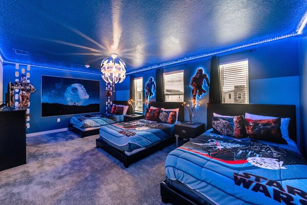 Ein Schlafzimmer mit zwei Betten, Star Wars-Betwäsche, einem großen Globus-Kunstwerk und einem Kronleuchter.