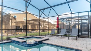 Ein von Glas umgebener Swimmingpool mit Whirlpool, umgeben von Liegestühlen und einem roten Sonnenschirm.