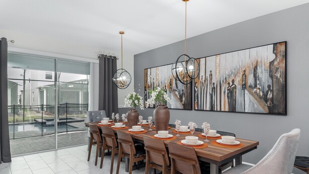 Un comedor moderno con una mesa grande dispuesta para seis personas, rodeada de sillas. Un cuadro abstracto de grandes dimensiones decora la pared, y hay una puerta de vidrio que da a un espacio exterior.