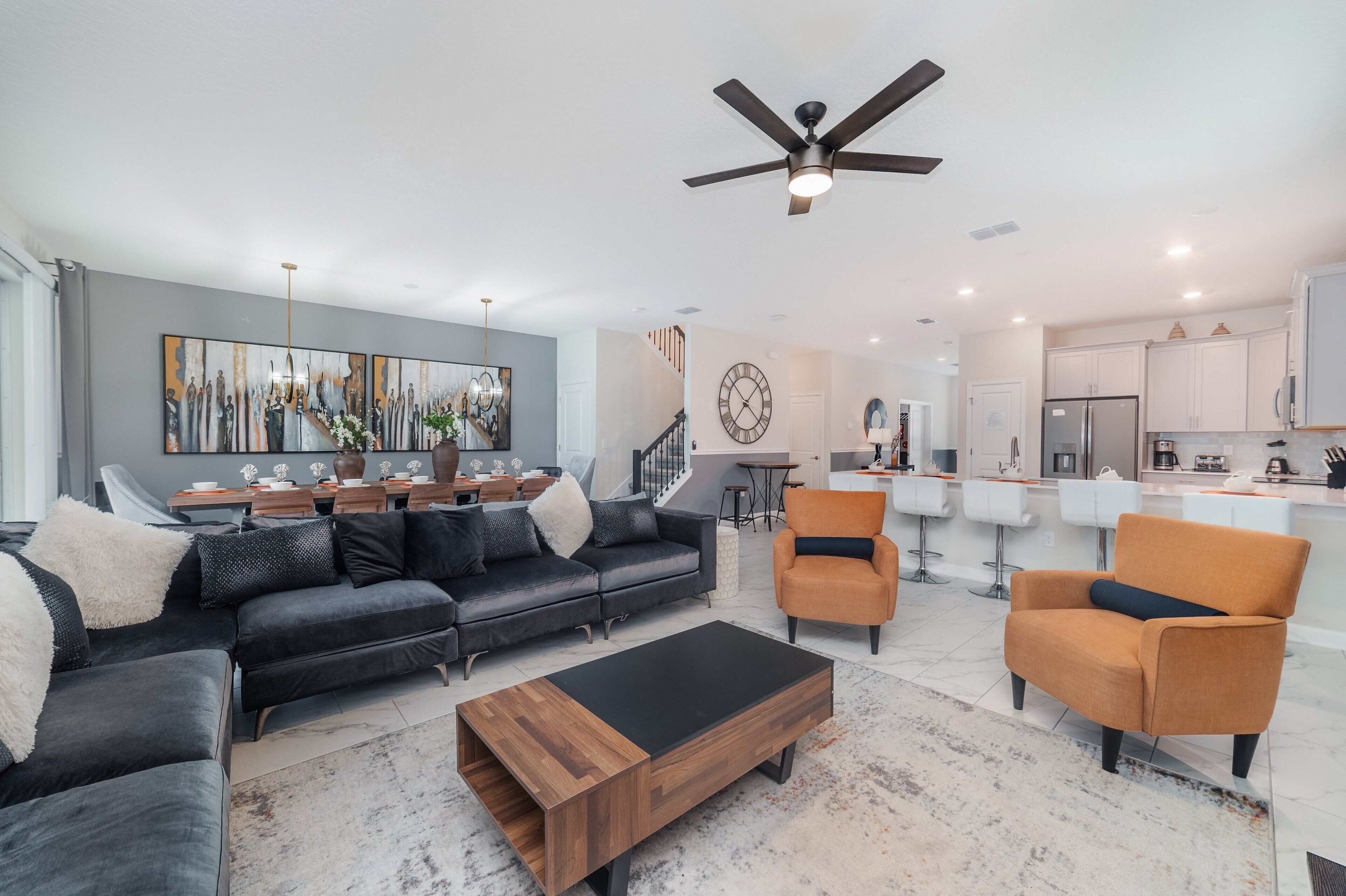 A modern living room with a black sectional sofa, a wooden coffee table, and an orange armchair.