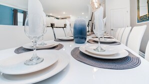 Zona de dinar amb taules i coves blanques, incloent plats, gots i un ram de flors decoratiu.