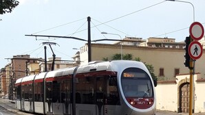 Un tranvía moderno con una pantalla digital que muestra la ruta T2 Unita, circulando sobre rieles con cables aéreos.