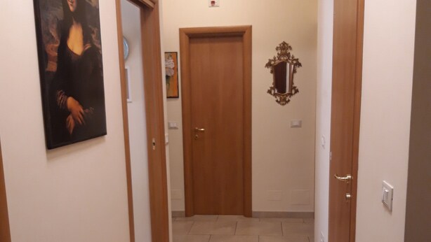 Un pasillo con piso de baldosas, puertas de madera y un cuadro en la pared.