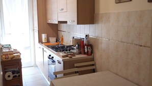 Una cocina con armarios de madera, estufa a gas y una mesa de comedor.