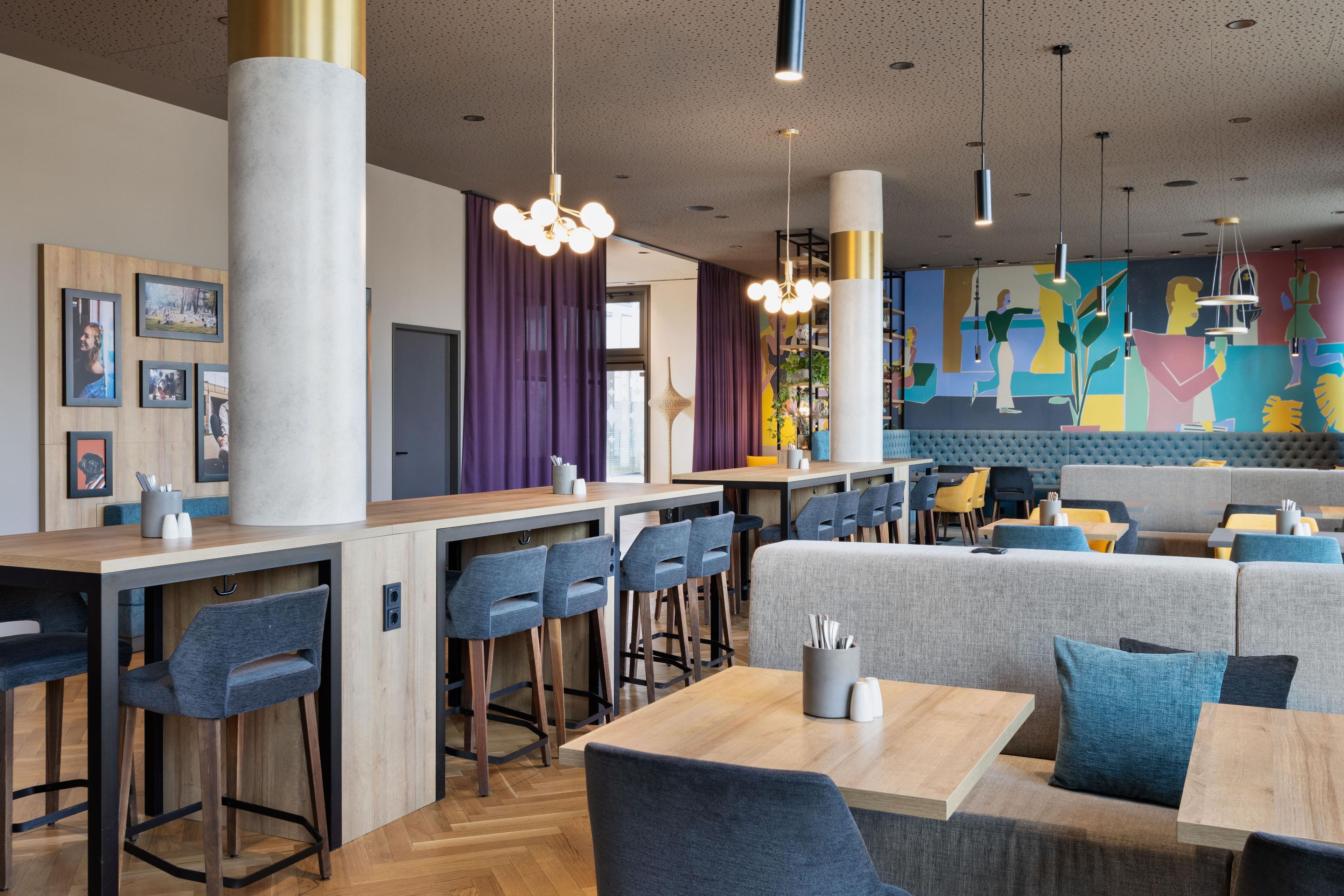 A modern restaurant interior with high stools, a bar area, and a colorful mural on the wall.
