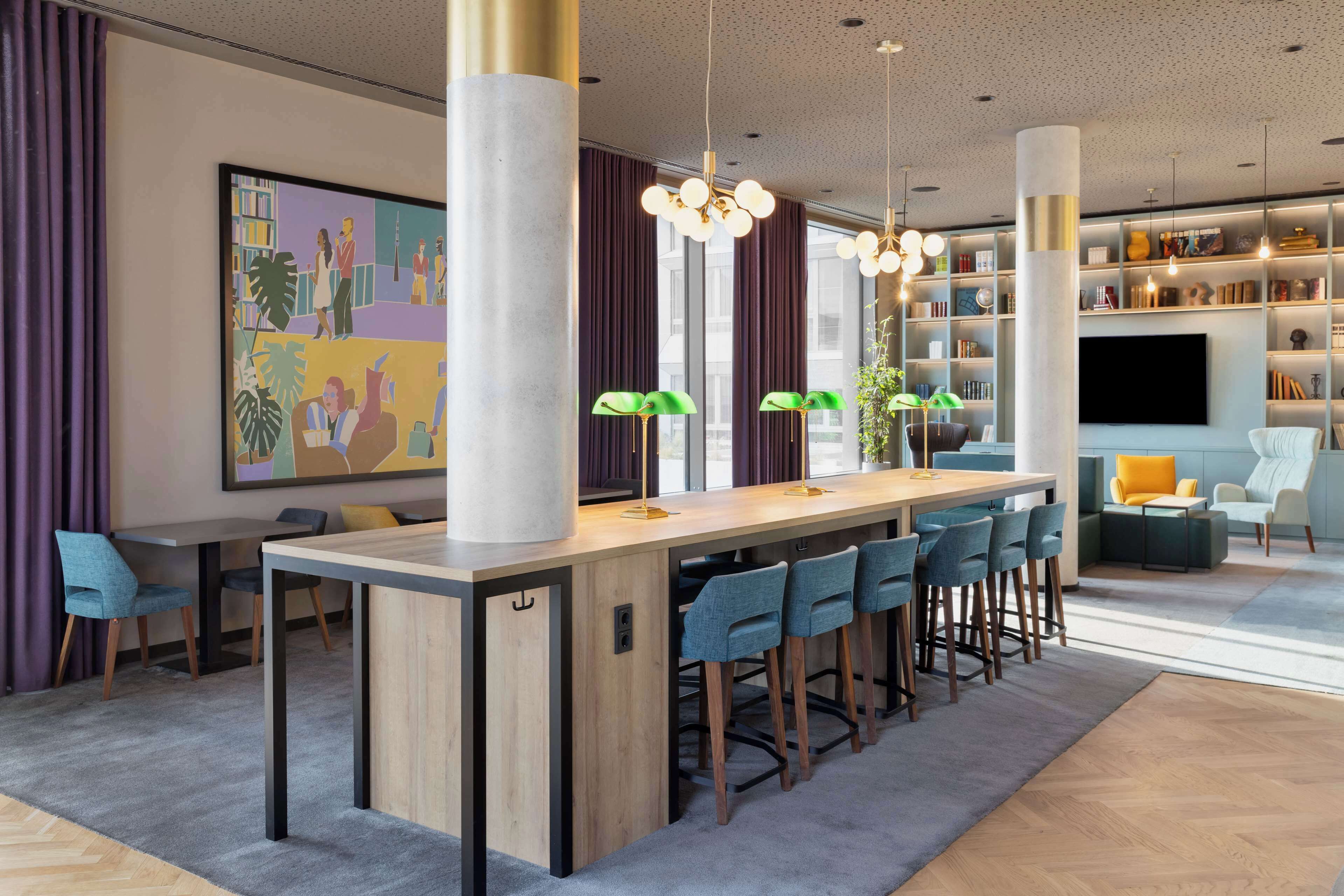 Een modern interieur met een centrale bar, zitplaatsen, een grote boekenkast en een flatscreen televisie.