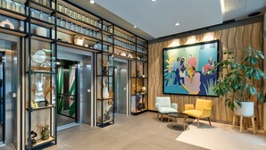 Una hall moderna con un grande dipinto astratto, una reception e un’area salotto con due poltrone.