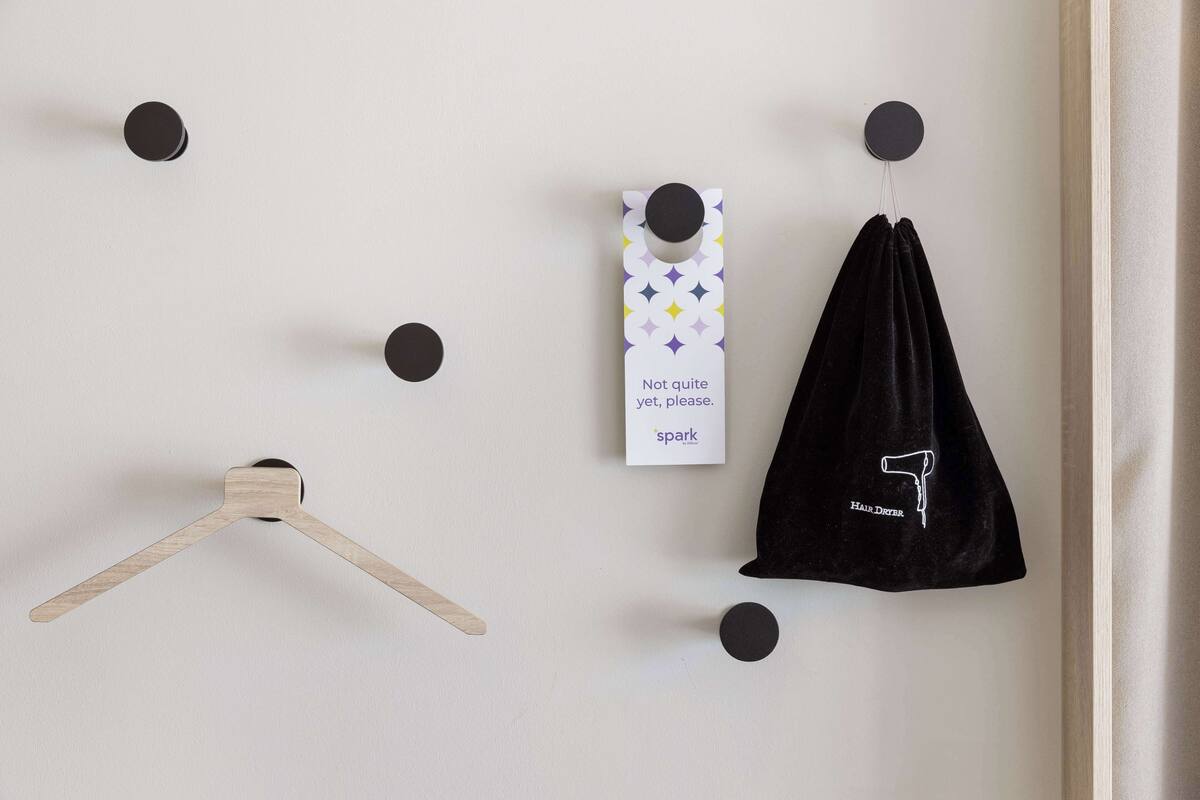 A wall with a wooden hanger, a black towel, and a sign with text.