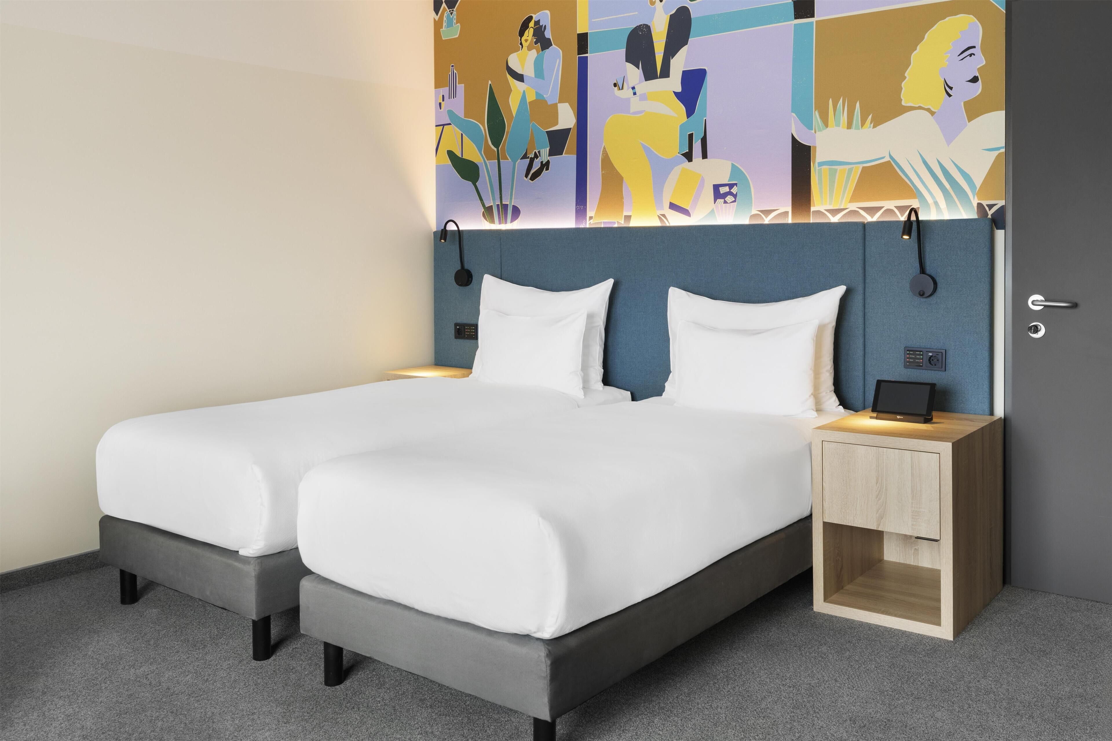 A double bed with a headboard, bedside tables, and a wall with abstract art.
