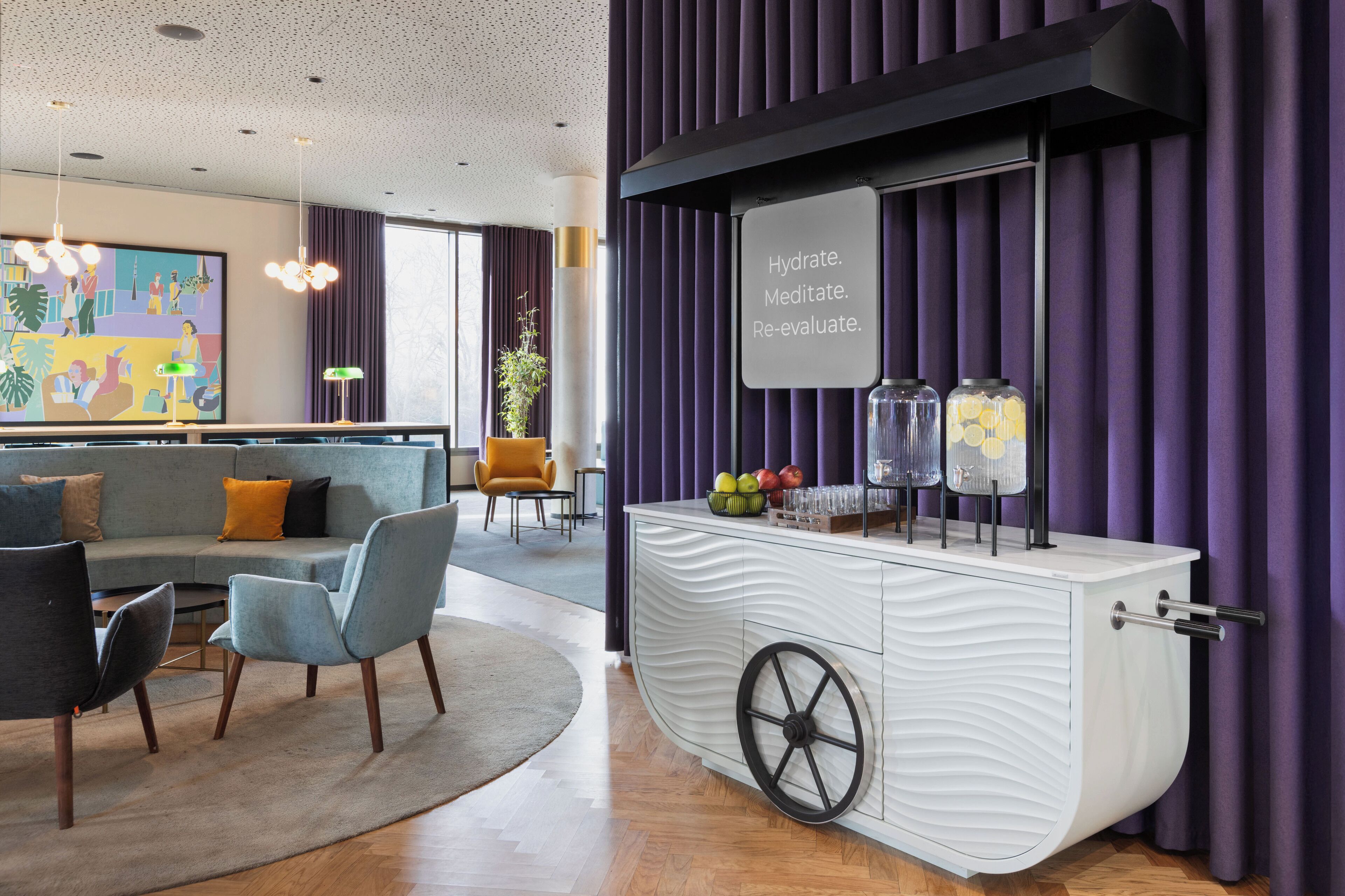 Eine moderne Lobby mit Sitzgelegenheiten, einer Getränkeecke und einem großen Kunstwerk an der Wand.