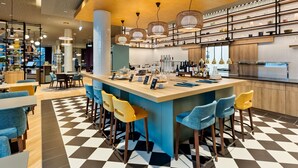 Un área de bar moderna con suelo a cuadros, taburetes y una isla central con barra.