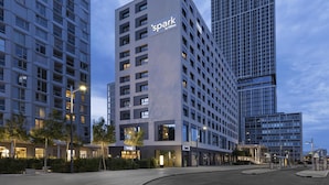 Un hotel moderno con il cartello 'spark by Hilton', immerso tra grattacieli e una strada cittadina ben illuminata.