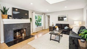A modern living room with a fireplace, a flat-screen TV, a sofa, and a coffee table. - The Elm House: Private Pool, Hot Tub, Napa Getaway (Napa)