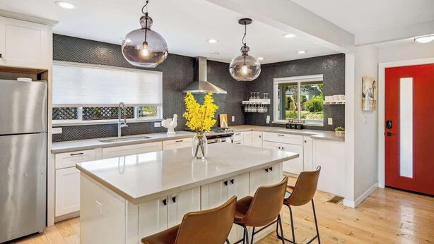 A modern kitchen with a large island, stainless steel appliances, pendant lighting, and a red door. - The Elm House: Private Pool, Hot Tub, Napa Getaway (Napa)