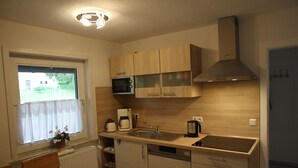 A compact kitchen with wooden cabinets, a microwave, a coffee maker, and a sink. - Apartment Julius 4 - nice, quiet and in the middle - (Sankt Andreasberg)