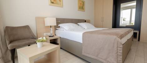 A bedroom with a bed, bedside table, lamp, and a chair.