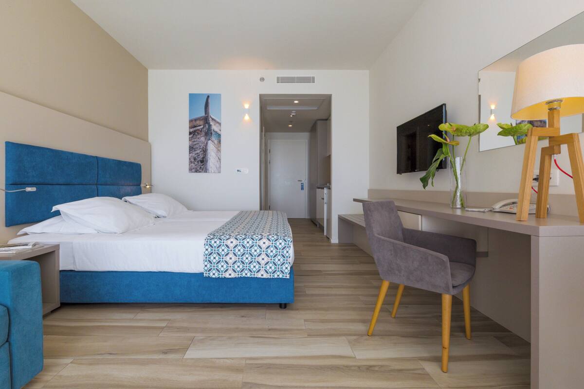 Een moderne hotelkamer met een bed, bureau, stoel en een televisie.
