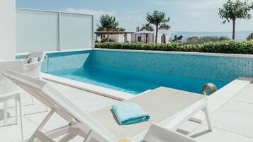 Zona de piscina con sillones de descanso y un vaso de jugo de naranja.