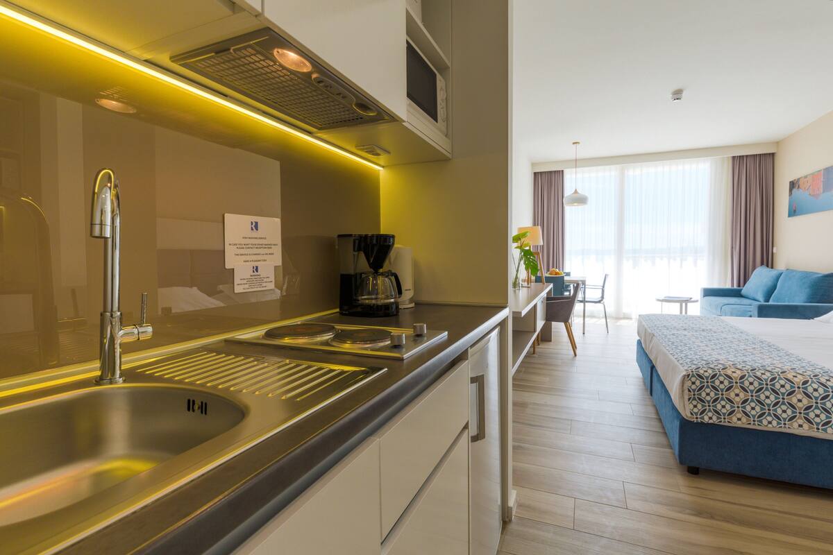 Een moderne hotelkamer met kitchenette, een bed, een eethoek en uitzicht op de stad.