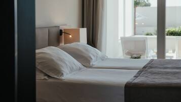 Una habitación de hotel con una cama, una mesita de noche y un ventanal con cortinas.