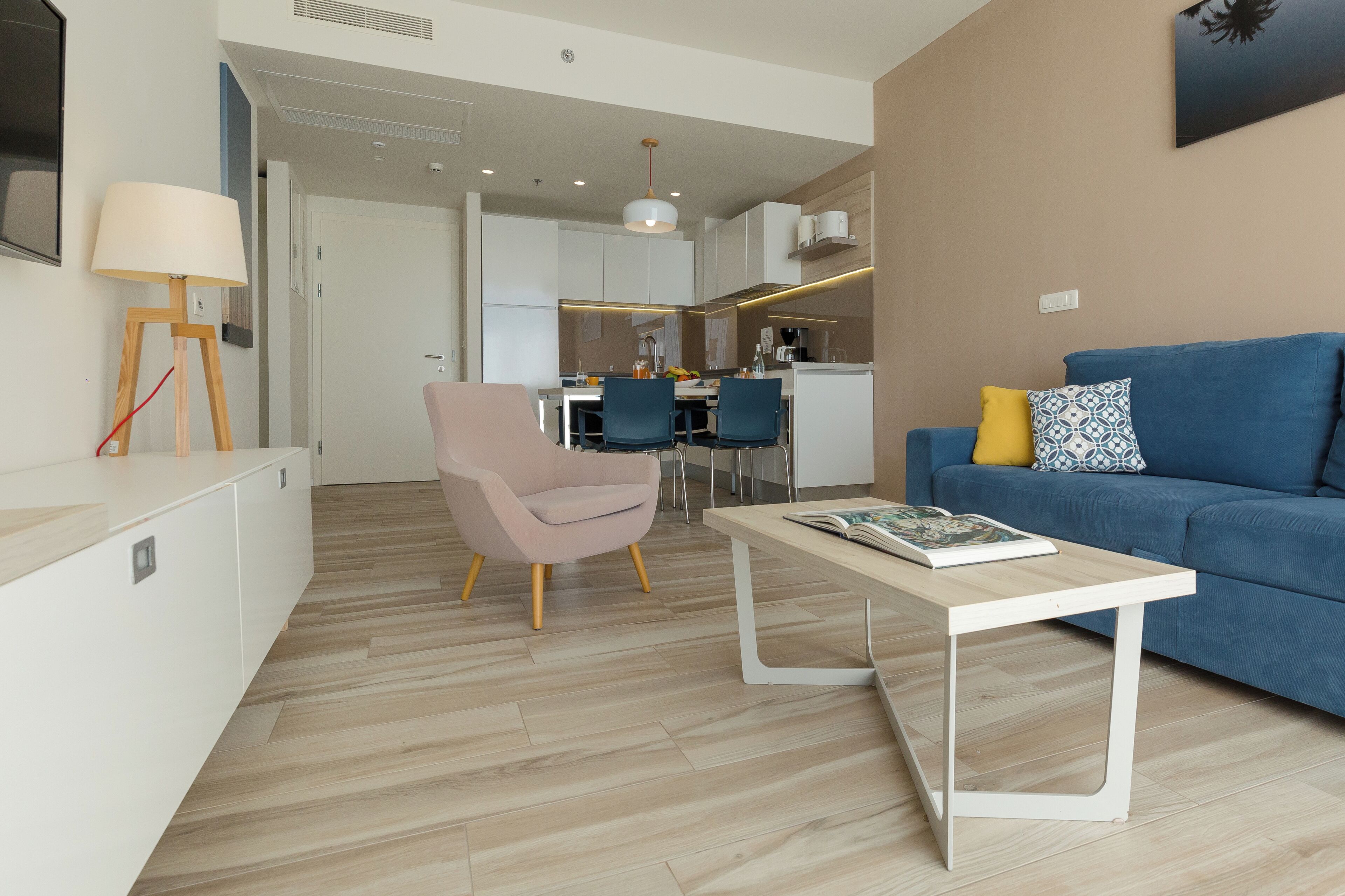 A modern living room with a blue sofa, a pink chair, and a white coffee table.