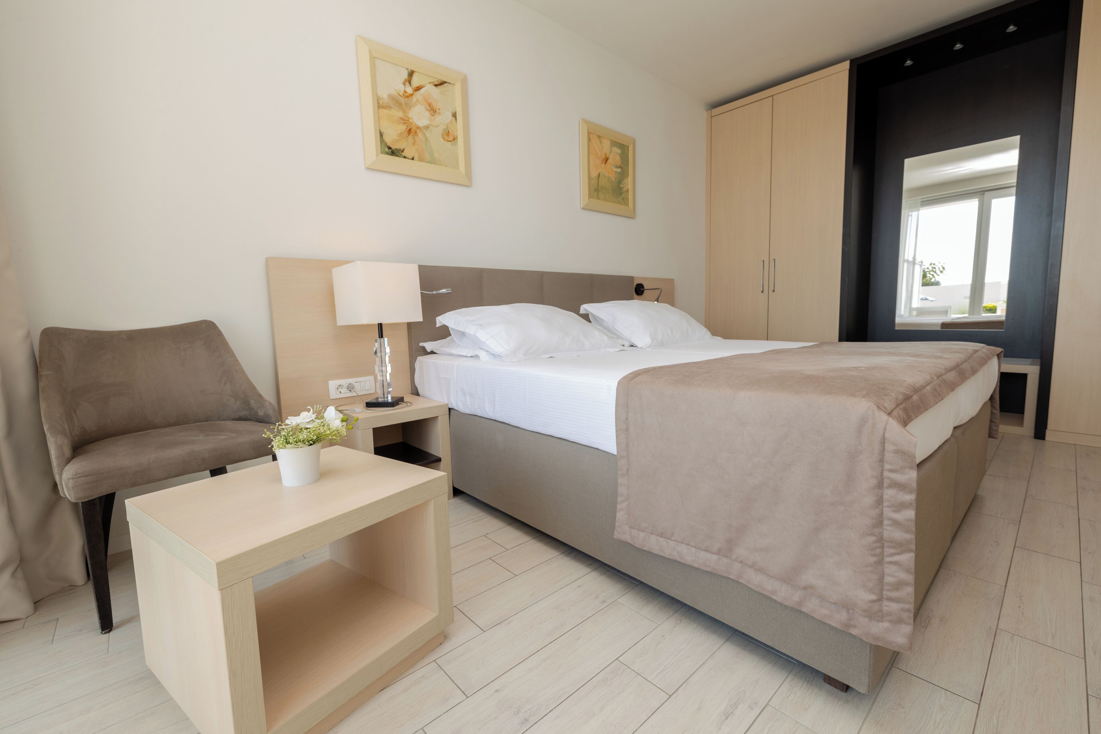 Ein Schlafzimmer mit Bett, Nachttisch, Lampe und Stuhl.
