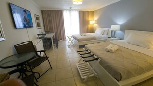 Een hotelkamer met een bed, een bureau, stoelen, een tafel, een lamp en een schilderij aan de muur.