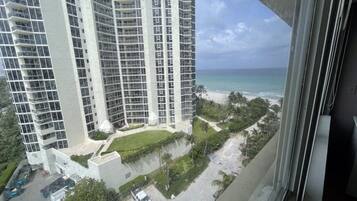 Um edifício alto com várias varandas dando para a praia e o oceano.