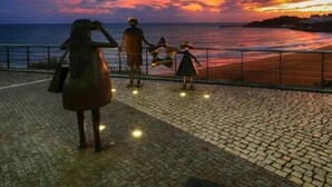 Vista del atardecer desde un paseo marítimo pavimentado con barandilla, con vista al mar.