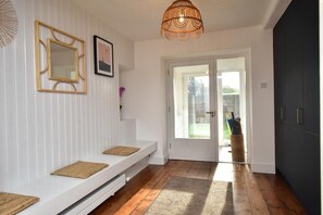 A modern interior with a white bench, a door leading outside, and a dark cabinet.
