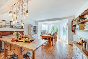 Una cocina amplia con una isla de madera, un comedor con sillas y vistas al exterior a través de ventanas grandes.