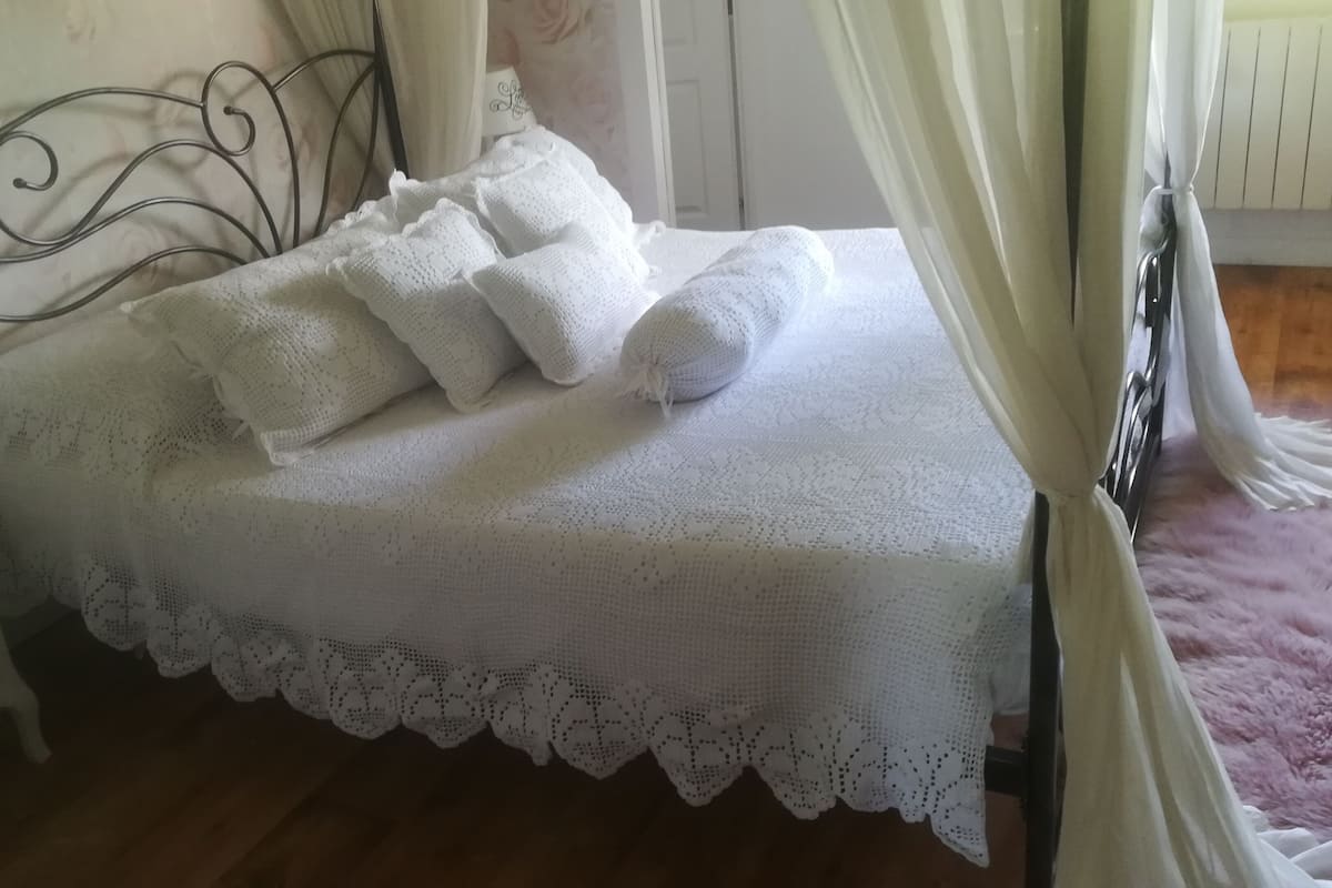 A neatly made bed with a white bedspread and pillows, a wooden headboard, and a nightstand with a lamp.