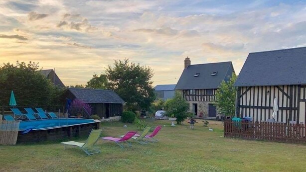 Un patio con piscina, sillas de descanso y casas tradicionales de entramado de madera.