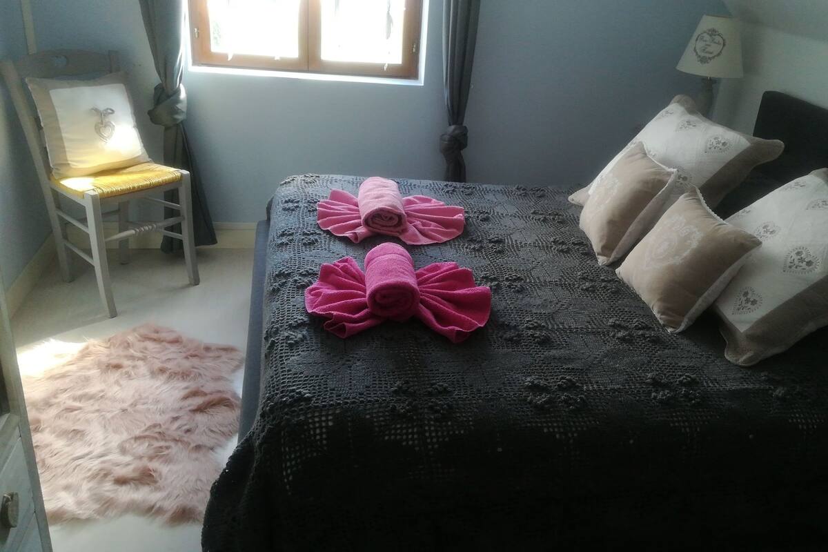 A bedroom with a bed, a chair, and a window.